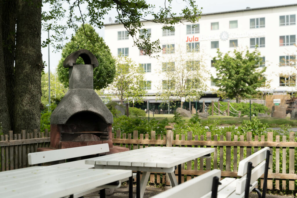 Utomhusugn och fikabord omgivna av trästaket med hotell i bakgrunden