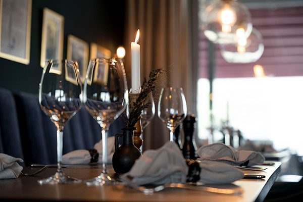 Elegant bordsdukning med vinglas, ljus och servetter i restaurangmiljö